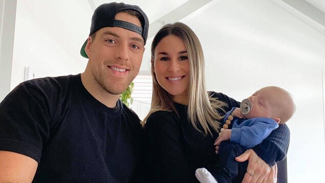 Alexandre Chevrier en train de signer son contrat avec les Alouettes, aux côtés de sa conjointe et de leur fils.
