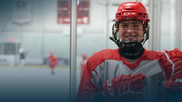 Une adolescente hockeyeuse regarde la caméra en souriant.