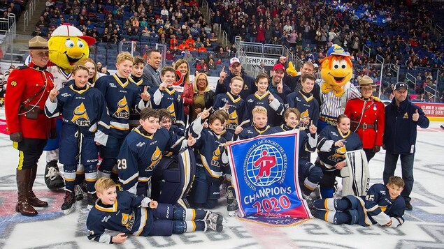 L'équipe pose pour une photo sur la glace avec la bannière de champions.