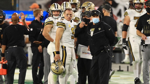 L'entraîneur-chef des Saints Sean Payton accompagné de joueurs sur la ligne de côté.