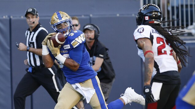 Les joueurs Andrew Harris et Sherrod Baltimore en pleine action sur le terrain pendant un match de football.