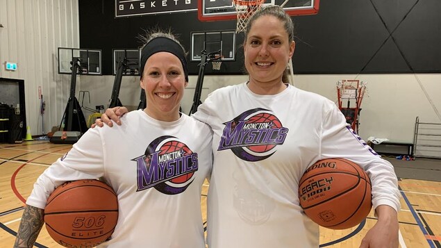 Deux femmes tenant des ballons de basketball et sourient.