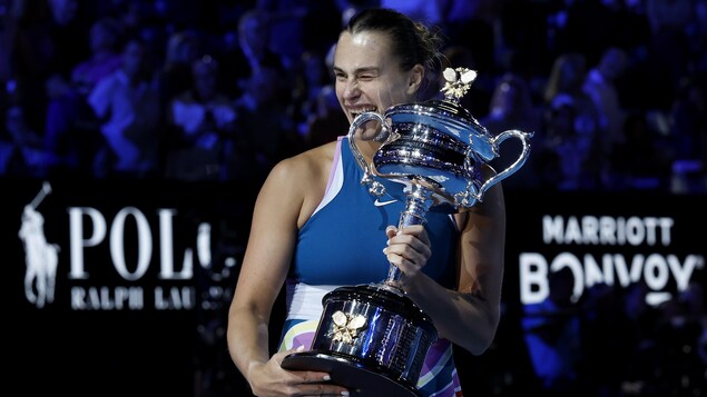 La joueuse de tennis Aryna Sabalenka croque un trophée.