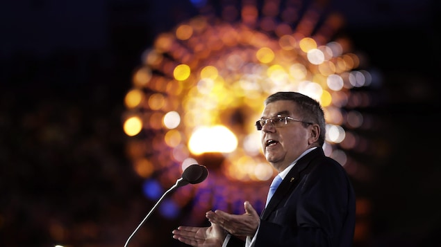 Un homme parle sur scène avec, derrière lui, des jeux de lumière.