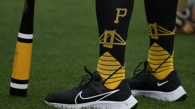 On aperçoit les mollets d'un joueur de baseball, qui porte des bas longs aux couleurs noir et jaune des Pirates.