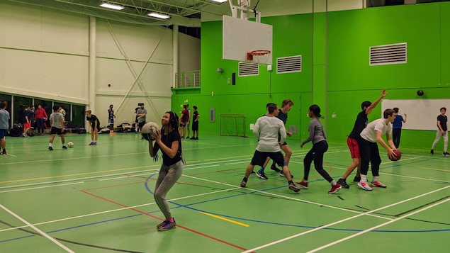 Des adolescents jouent au basketball et au soccer dans un gymnase.