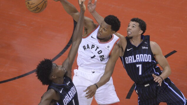 L'attaquant Jonathan Isaac et le garde Michael Carter Williams du Magic d'Orlando Magic tentent de soutirer le ballon au meneur de jeu torontois, Kyle Lowry.