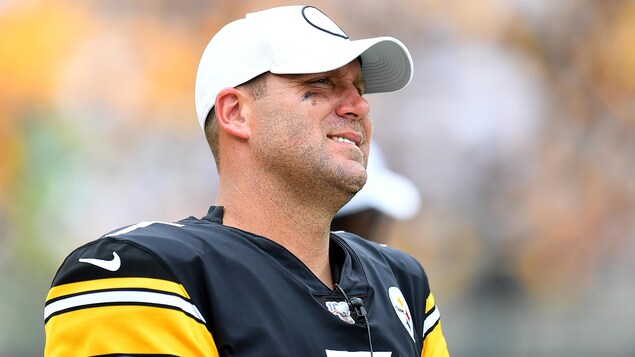 Un joueur de football en uniforme, avec une casquette, grimace