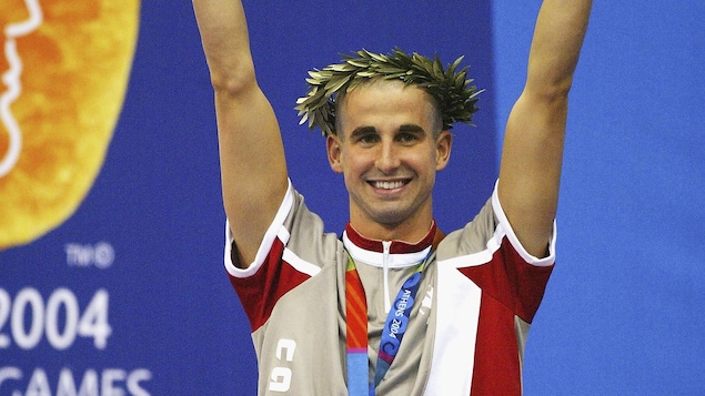 Il est sur le podium avec sa médaille d'or au cou et coiffé d'une couronne d'olivier.