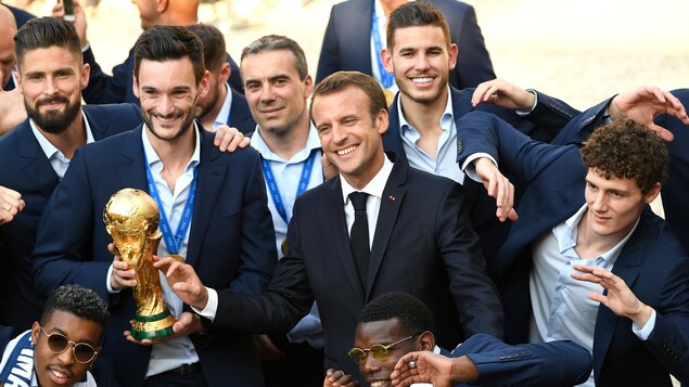 Hugo Lloris tient le trophée de la Coupe du monde à côté du président Macron et du reste de l'équipe de France Hugo Lloris tient le trophée de la Coupe du monde à côté du président Macron et du reste de l'équipe de France