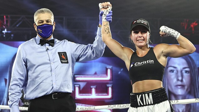 L'arbitre lève le poing de la boxeuse en signe de victoire.
