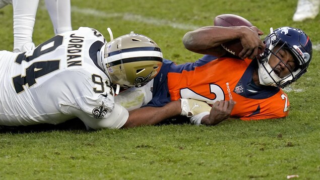 Deux joueurs de football étendus sur la surface de jeu après un sac du quart.