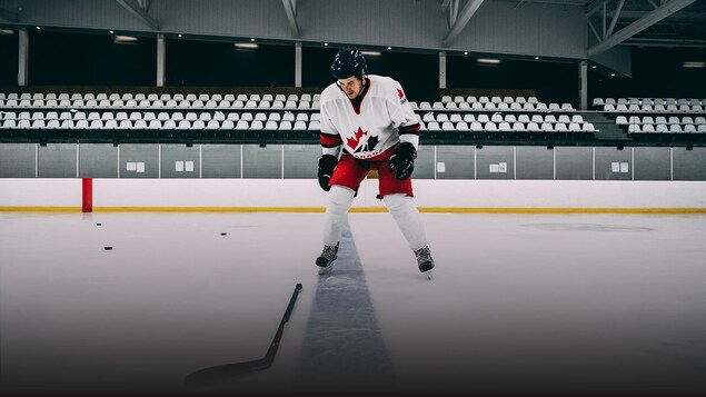 Le journaliste Michaël Roy se tient debout sur une patinoire vêtu d'un équipement de hockey.