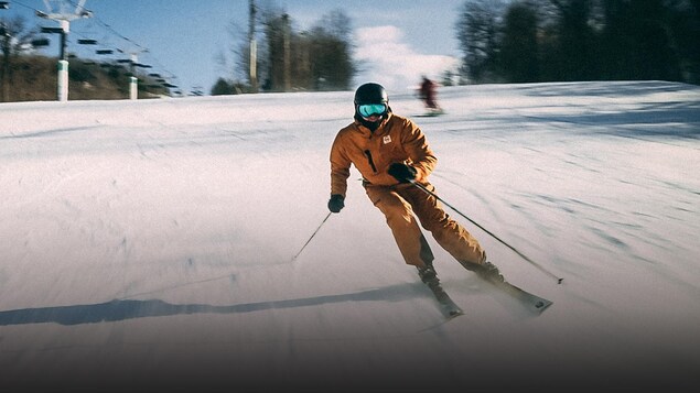 Un homme descend une pente en ski alpin.
