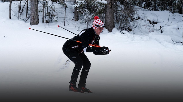 Photo d'un skieur de fond descendant une pente en forêt.