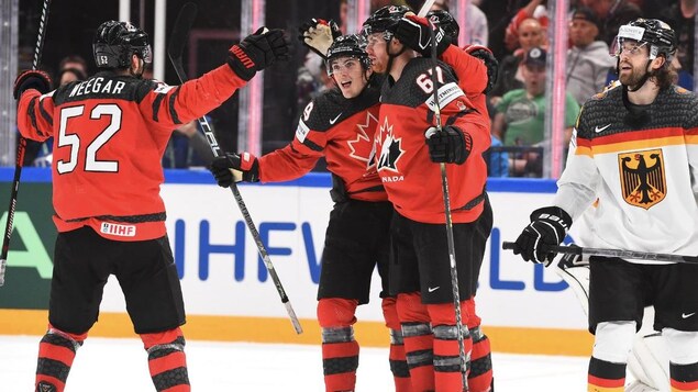 Trois joueurs de hockey du Canada ouvrent les bras pour célébrer un but.