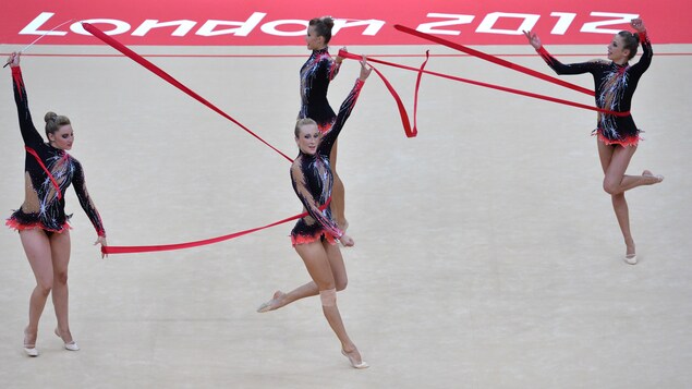 Quatre gymnastes font des figures avec des rubans rouges