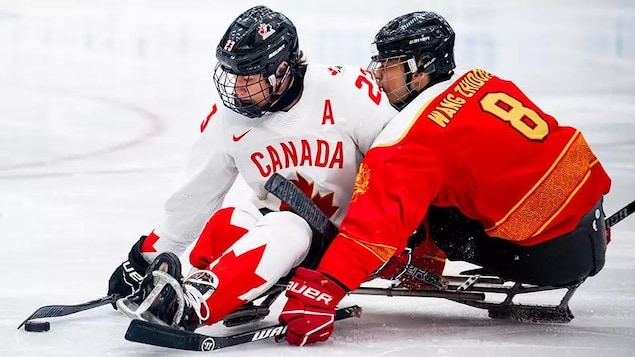 Un joueur de l'équipe canadienne de parahockey contrôle la rondelle devant un adversaire de la Chine. 