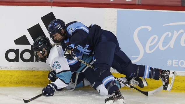 Une hockeyeuse en plaque une autre sur la glace.