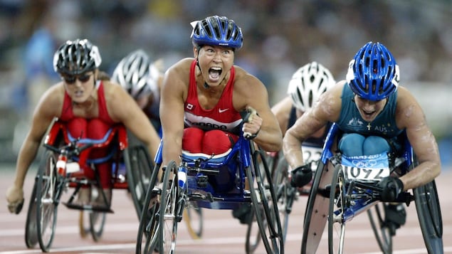 Une athlète en fauteuil roulant exulte après sa course.