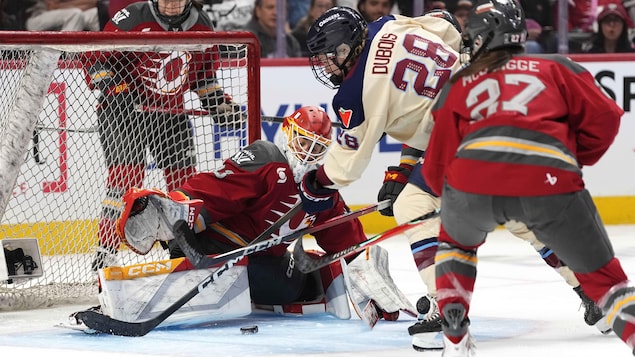 Une gardienne de but se dresse tel un mur devant une attaque lors d'un match de hockey féminin professionnel.