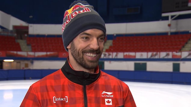 Il sourit sur le bord de la patinoire.