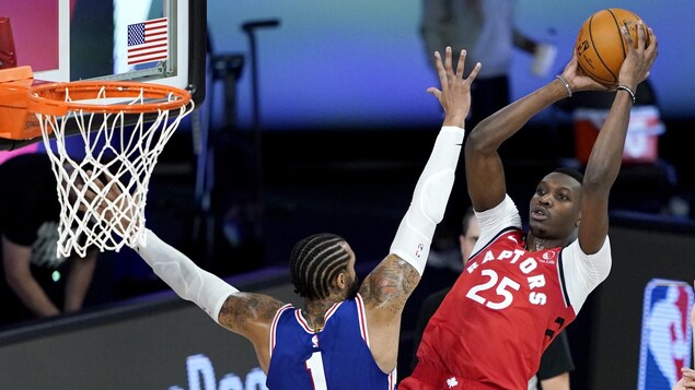 Chris Boucher tente de lancer un ballon malgré la couverture d'un adversaire.