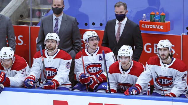 Les entraîneurs se tiennent debout et portent un masque.