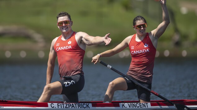 Deux athlètes dans un canoë sourient après leur victoire.