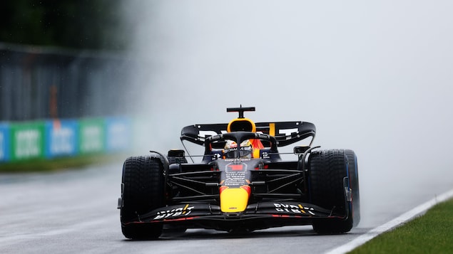 Un bolide de formule 1 soulève un nuage de gouttelettes sur son passage.