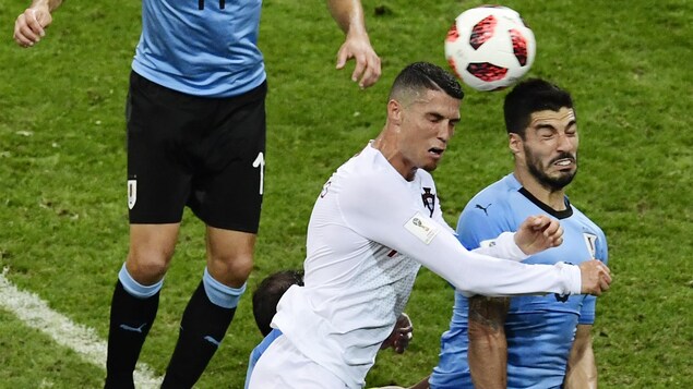Le Portugais et l'Uruguayen tentent de frapper le ballon de la tête. Le Portugais et l'Uruguayen tentent de frapper le ballon de la tête.