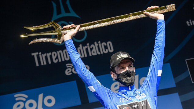 Il soulève le trophée remis au vainqueur.