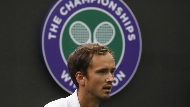 Concentré, il regarde la balle devant un logo de Wimbledon.