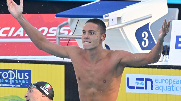 Un nageur soulève les bras et serre les dents.