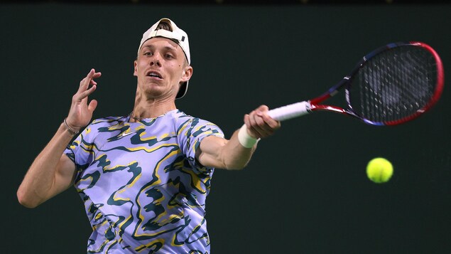 Un joueur de tennis frappe une balle de son coup droit.