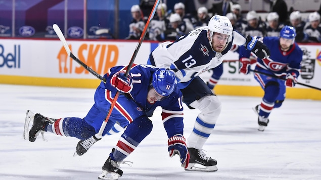 Brendan Gallagher perd pied devant l'attaquant des Jets, les deux joueurs à la poursuite de la rondelle.