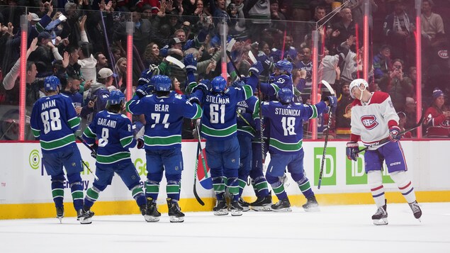 Des hockeyeurs célèbrent une victoire devant un rival ayant la tête baissée.