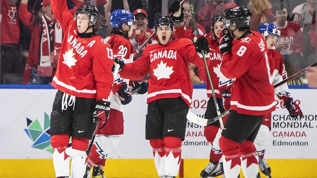 Des hockeyeurs canadiens célèbrent un but sur la patinoire.