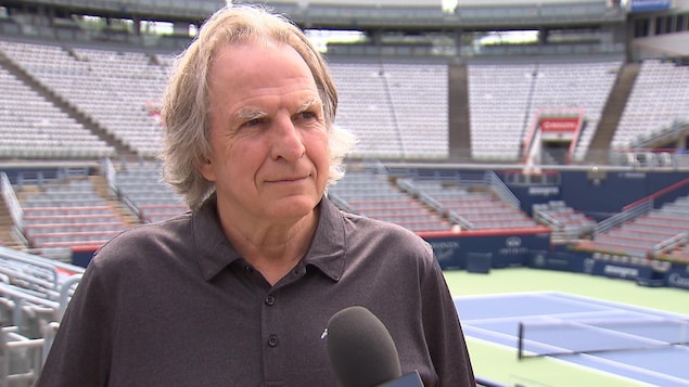 Le directeur de la Coupe Rogers à Montréal, Eugène Lapierre, sourit en regardant le journaliste à la droite de l'écran.