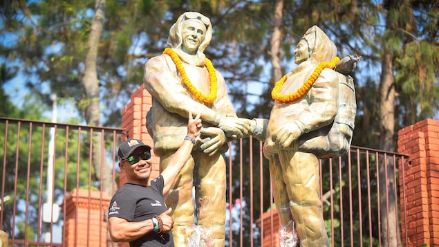 Un homme pose devant des statues.