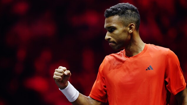 Un joueur de tennis, vêtu de rouge, montre le poing après avoir remporté un échange. 