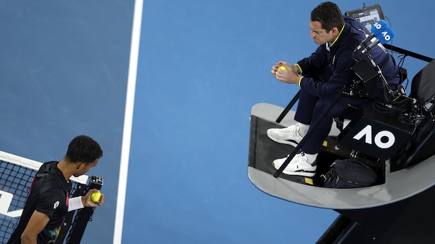 Un joueur de tennis discute avec l'arbitre de la mauvaise qualité des balles. 