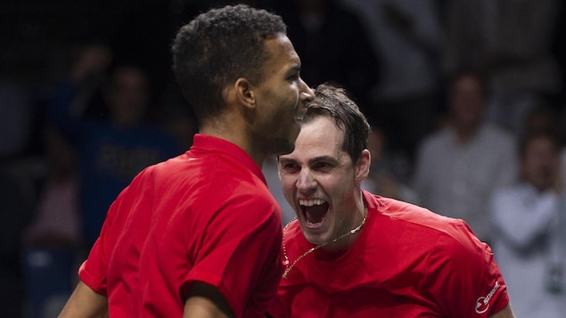 Deux joueurs de tennis habillés de rouge, tout sourire.