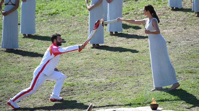 L'actrice grecque Xanthi Georgiou allume le flambeau tenu par le skieur grec Giannis Antoniou.