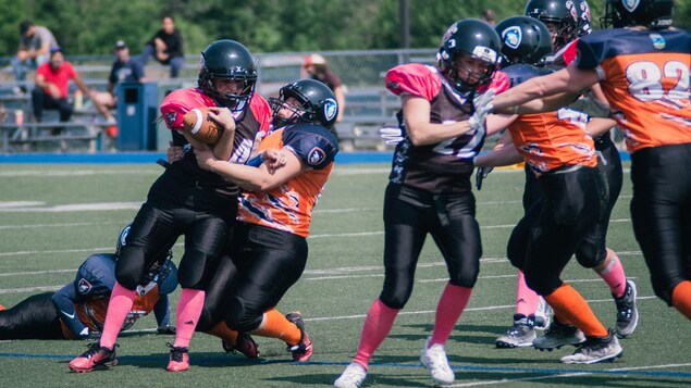 Une femme se fait plaquer au football. 