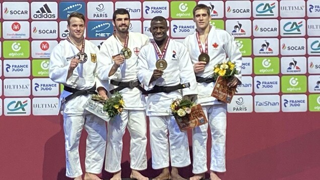 Quatre judokas présentent leur médaille.