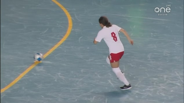 Une joueuse se prépare à donner un coup de pied sur un ballon.