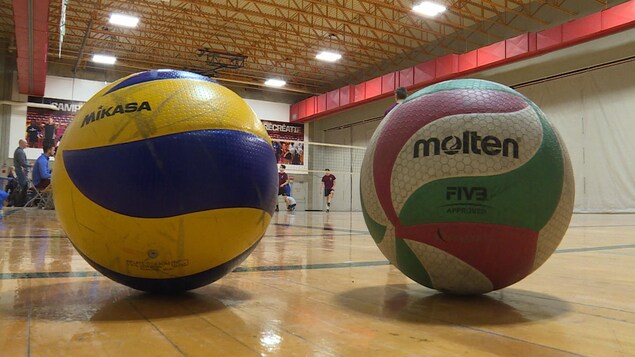 Deux ballons, un Mikasa et un Molten sont un à côté de l'autre sur un terrain de volleyball