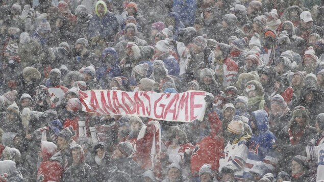 Des partisans canadiens soutiennent que le hockey est leur sport, banderole à l'appui, au match entre le Canada et les États-Unis en plein air au New Era Field. Des partisans canadiens soutiennent que le hockey est leur sport, banderole à l'appui, au match entre le Canada et les États-Unis en plein air au New Era Field.