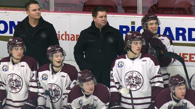 Mike Reagan derrière le banc des Broncos. Ses joueurs et lui regardent attentivement le match.